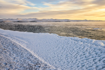 Ice floes floating on the fog water in the lake Baikal. Sunset