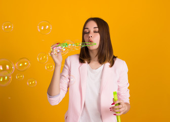 Young cute girl blows soap bubbles, isolated  