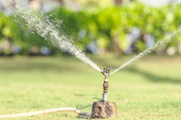 Simple modern automatic sprinkler system on the grass in the park of Bali island, Indonesia.