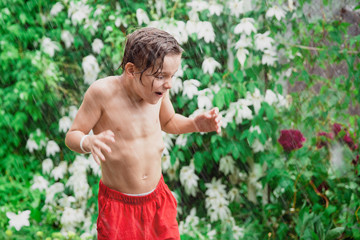 Boy jumping and splashing in rain puddle