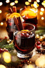 Mulled wine, Christmas hot drink with addition aromatic spices, citrus fruit and cranberries on a wooden rustic table