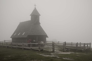 Wooden church in mist in Velika Planina (Slovenia)
