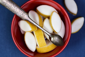 French calissons sweets in a red bowl with an old sugar spoon on blue background.