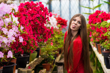 Pretty smiling young women with very long hair in a red blouse in a rose garden