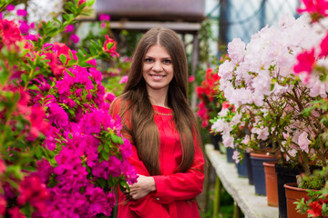 Pretty smiling young women with very long hair in a red blouse in a rose garden