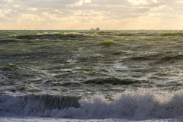 Ship in the horizon of a stormy green sea