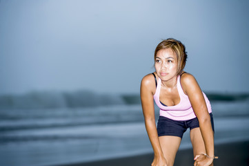 Fototapeta na wymiar fit Asian sport runner woman cooling off breathing after running on beach sea side looking tired while hard workout