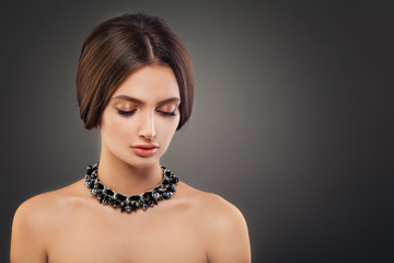 Beautiful Young Woman Fashion Model with Pearls Necklaces and Makeup on Dark Background