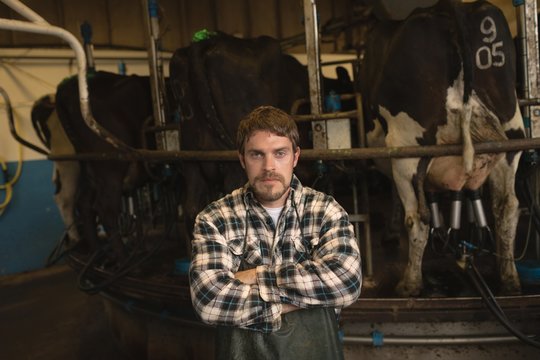 Confident milker standing with arms crossed in shed