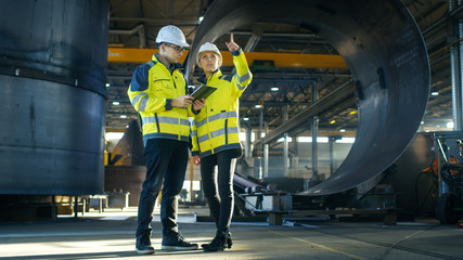 Male and Female Industrial Engineers in Hard Hats Discuss New Project while Using Tablet Computer....