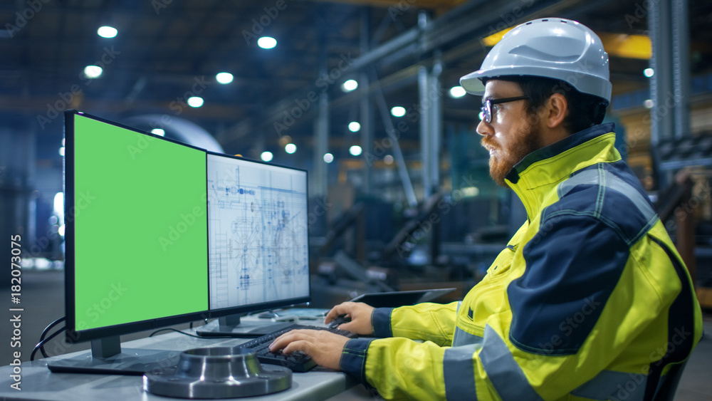 Poster inside the heavy industry factory industrial engineer works on the personal computer with two screen