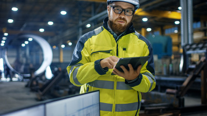 Inside the Heavy Industry Factory Female Industrial Engineer Works on Personal Computer She Designs 3D Engine Model, Her Male Colleague Talks with Her and Uses Tablet Computer.
