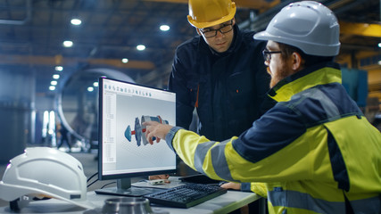 Fototapeta premium Inside the Heavy Industry Engineer Works on the Personal Computer while Talking with the Project Manager. He Designs Turbine/ Engine in 3D CAD Program.
