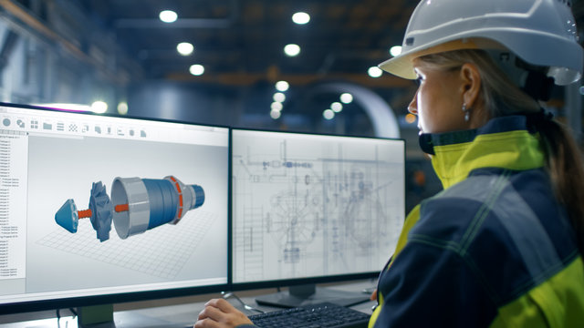 Inside the Heavy Industry Factory Female Industrial Engineer Works on the Personal Computer on the Turbine/ Engine Project in 3D Using CAD Program.