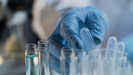 Lab assistant carrying out tests in laboratory, examining liquid substances