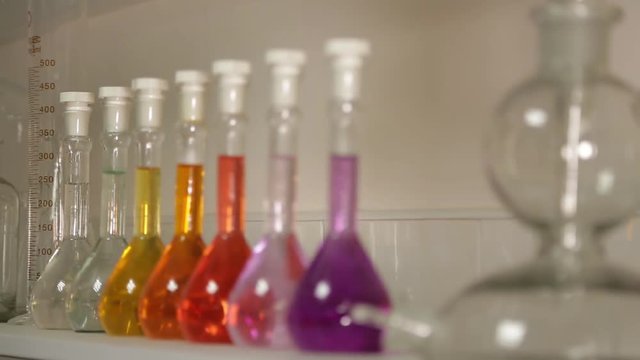 Measuring cups on lab table. Lab flasks with chemical liquids. Laboratory glassware with color liquid and with reflection. Fluid in laboratory flasks.