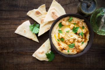 Chickpea hummus garnished with paprika, parsley leaves and olive oil and served with pita bread. Overhead view