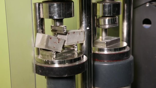Testing of concrete samples for strength. Concrete block is checked for fracture strength in a laboratory press at a cement plant.