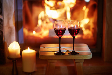 Two glasses of red wine near fireplace