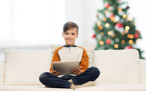 smiling boy with tablet pc at home at christmas