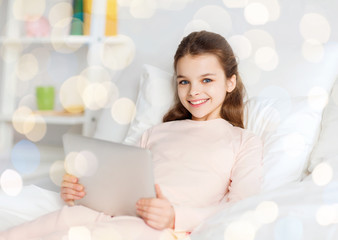 happy girl in bed with tablet pc over lights