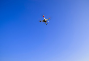 The flight of the Copter in the clear blue sky. White drone.