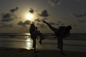 Karate fighters at sunset on the beach