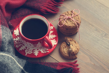 Red Christmas mug with coffee and cookies on the wooden table