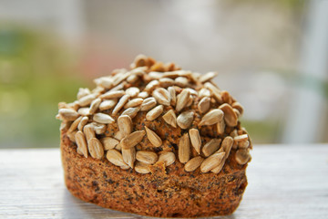 Freshly baked raisins cake with sunflower seeds isolated on white wooden board. Healthy vegetarian muffin on blurred nature background. Close up view