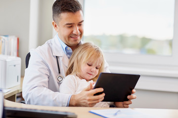 doctor and little girl with tablet pc at clinic