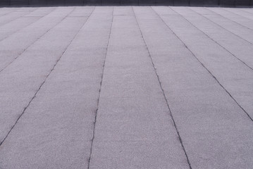 Flat surfaced roof coating. Heating and melting bitumen roofing felt background pattern.