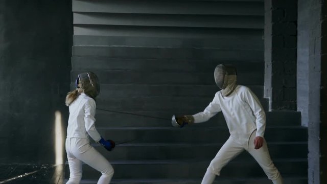 Slowmotion of Two fencers man and woman have fencing training indoors