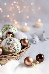 Christmas ornaments in a wicket basket, put on a snow top. Focus on painted christmas balls....