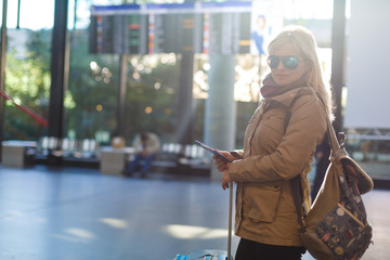 Young woman traveler in international airport with backpack holding passport in her hand