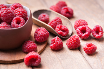 Raspberries in a cup and wooden scoop