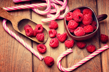 Raspberries in a cup, candy canes and wooden scoop 