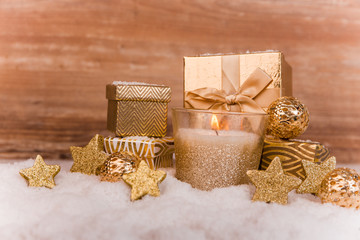 Fototapeta na wymiar Goldene brennende Kerze mit Weihnachtsdeko