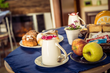 Table with the breakfast. Apples,  croissant and white coffee cup