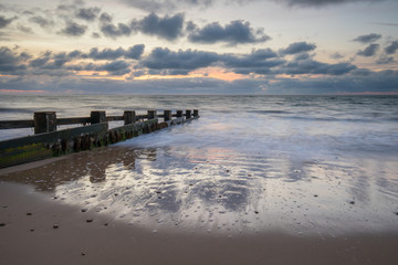 sunrise over groynes in bay