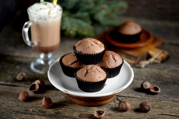 Delicious homemade chocolate muffins with cocoa and raisins on an old wooden background.