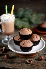 Delicious homemade chocolate muffins with cocoa and raisins on an old wooden background.