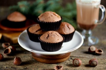 Delicious homemade chocolate muffins with cocoa and raisins on an old wooden background.