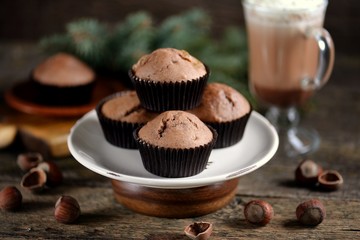 Delicious homemade chocolate muffins with cocoa and raisins on an old wooden background.