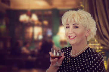 Cool-looking blond mature woman drinks brandy