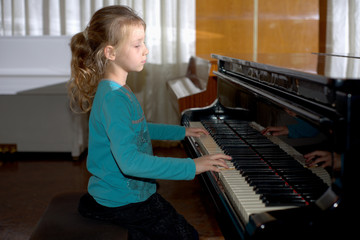 The girl plays piano, close up , white and black keyboard