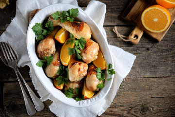 Baked chicken drumstick with orange  on an old wooden background. Rustic style.