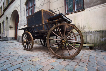 Fototapeta na wymiar Vintage wooden cart on a cobble stone street in an old town