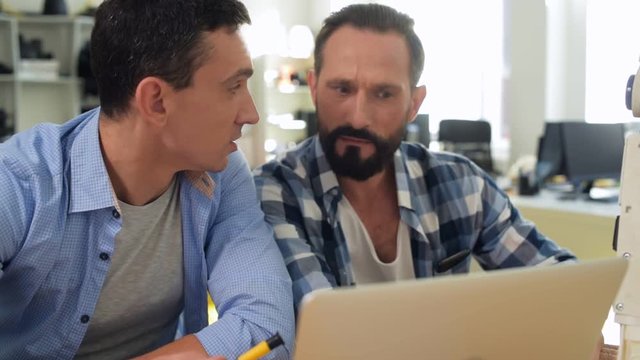 Busy day. Close up of enthusiastic constructors using a laptop and consulting the internet while working on new mockup