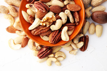 bowl with mixed nuts on white background. Healthy food and snack. Walnut, pecan, almonds, hazelnuts and cashews