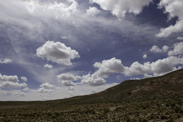 A fisheye bubble wide angle lens huge blue sky with fluffy clouds in windy mountain range of the Altiplano, Bolivia with the sparse brush of the desert below
